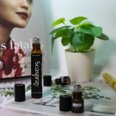 Close-up of essential oil bottles on magazines beside a green potted plant and bamboo sticks, creating a calm, natural wellness scene